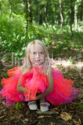 Sad little girl in fairy costume in a forest