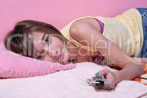 Teenage girl laying on the bed with remote control