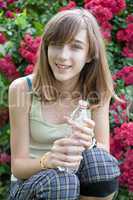 Teenage girl with bottle of water in the rose garden