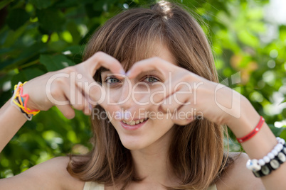 Happy teenage girl forming heart with her hands