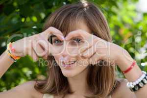 Happy teenage girl forming heart with her hands