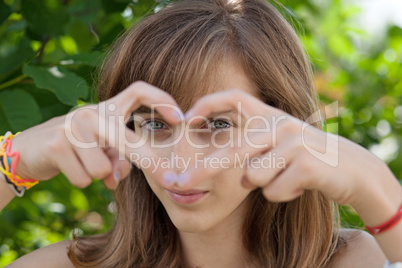Teenage girl forming heart with her hands