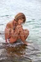 Teenage girl sitting on a rock in the sea
