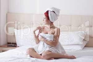 Beautiful red-haired woman posing on hotel bed