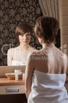 Slender brunette in towel posing near mirror