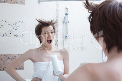 Cheerful girl posing with hairdryer near mirror