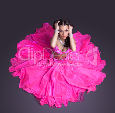 Pretty dancer in pink costume sitting on floor