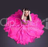 Pretty dancer in pink costume sitting on floor