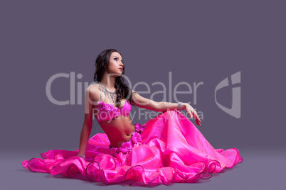 dancer in oriental pink costume sitting on floor