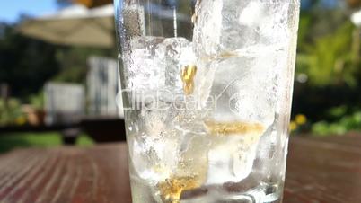 Pouring cola in glass with ice cubes