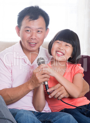 Happy Asian family singing karaoke