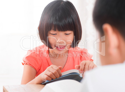 Asian children reading book at home