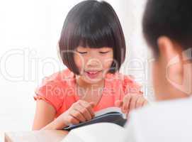 Asian children reading book at home