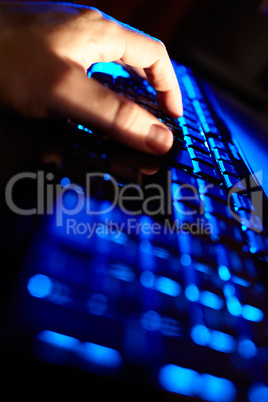 Man's hand typing on a blue keyboard.