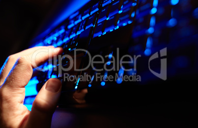 Man's hand typing on a blue keyboard.