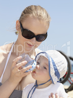 Young mother feeding her son at the beach.