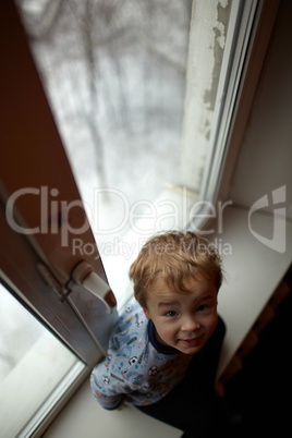 Smiling boy sitting on the windowsill.