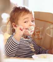 Two year old boy eats porridge in the morning.