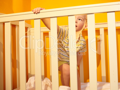 Little boy stands in bed