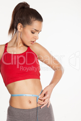 Shapely young woman measuring her waist