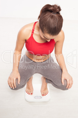 woman crouching to read her weight