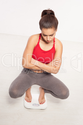 woman crouched on a bathroom scale