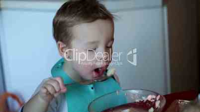 Two year old boy is eating soup from the plate. Clip one.