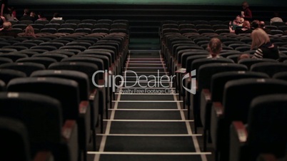 Audience fills the theatre. Time lapse.
