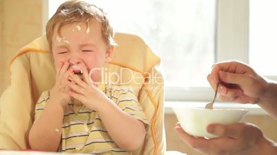 Little boy is crying because he doesn't want to eat more cereal.