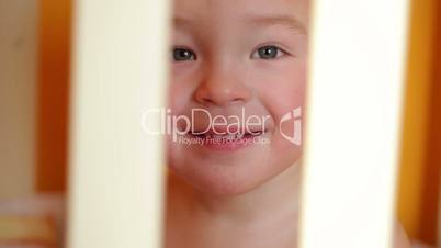 Portrait of the smiling little boy sitting in the playpen.
