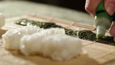 Putting wasabi on the nori while cooking sushi rolls.