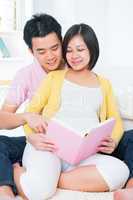 Asian pregnant couple reading book