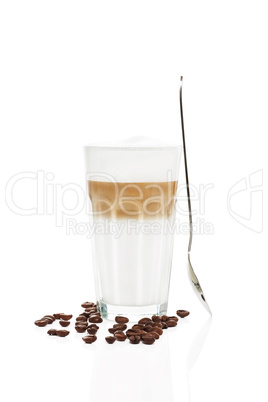 latte macchiato mit stehendem löffel und kaffeebohnen
