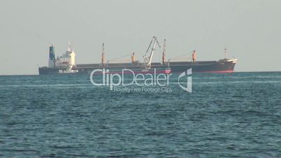 Cargo ship and small ship floating at surface of sea
