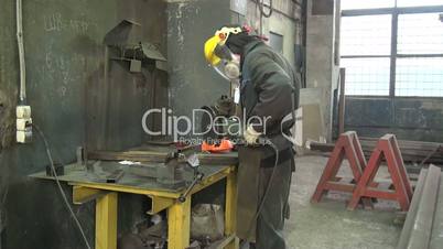 Manual worker in steel factory using circular blade on a piece of metal