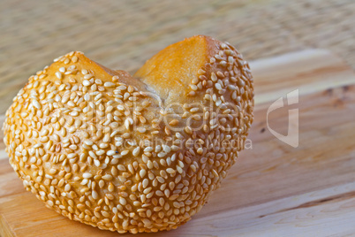 Brötchen in Herzform mit Sesam auf Holzbrett