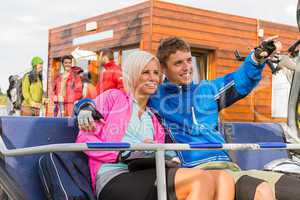Cheerful couple sitting chair lift man pointing