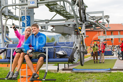 Happy couple traveling chair lift enjoying landscape