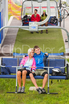 Cuddling couple pointing chair lift in sweatsuits