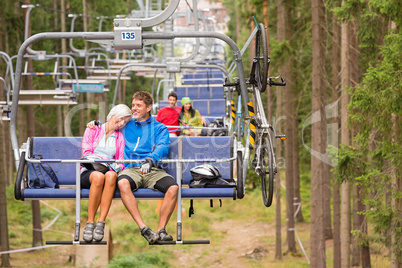 Carefree couple traveling by chair lift wood