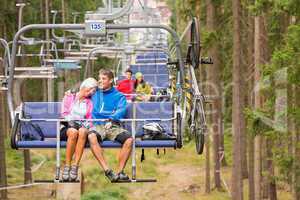 Carefree couple traveling by chair lift wood