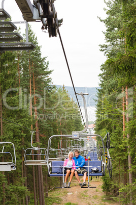 Young couple sitting on chair lift landscape