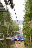 Young couple sitting on chair lift landscape