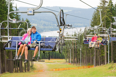 Smiling couples using chair lift scenic landscape