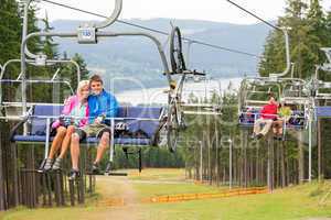 Smiling couples using chair lift scenic landscape