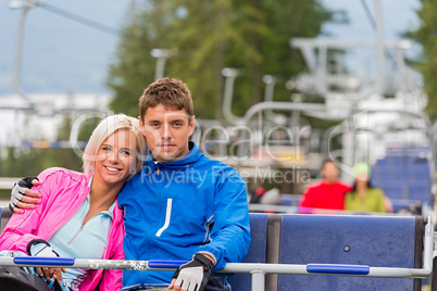 Hugging young couple sitting on chair lift