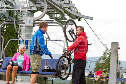 Man helping couple holding bicycle chair lift