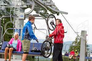 Man helping couple holding bicycle chair lift