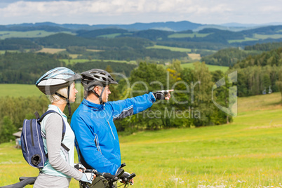 Pointing cyclists couple on summer weekend nature