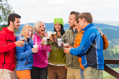 Happy friends clinking glasses drinking beer outdoors